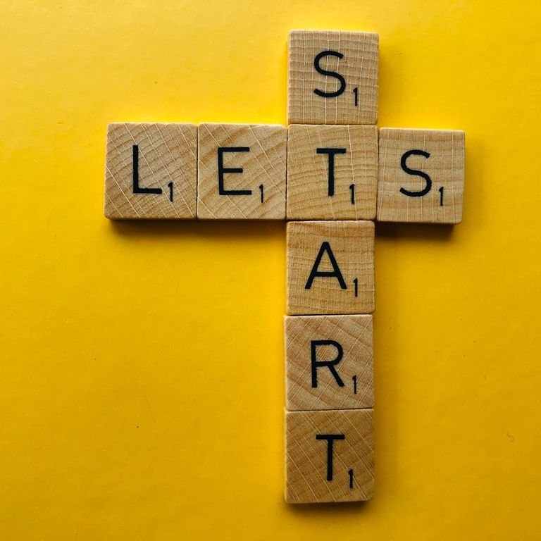 A bright yellow background with wooden scrable tiles spelling out Let's Start